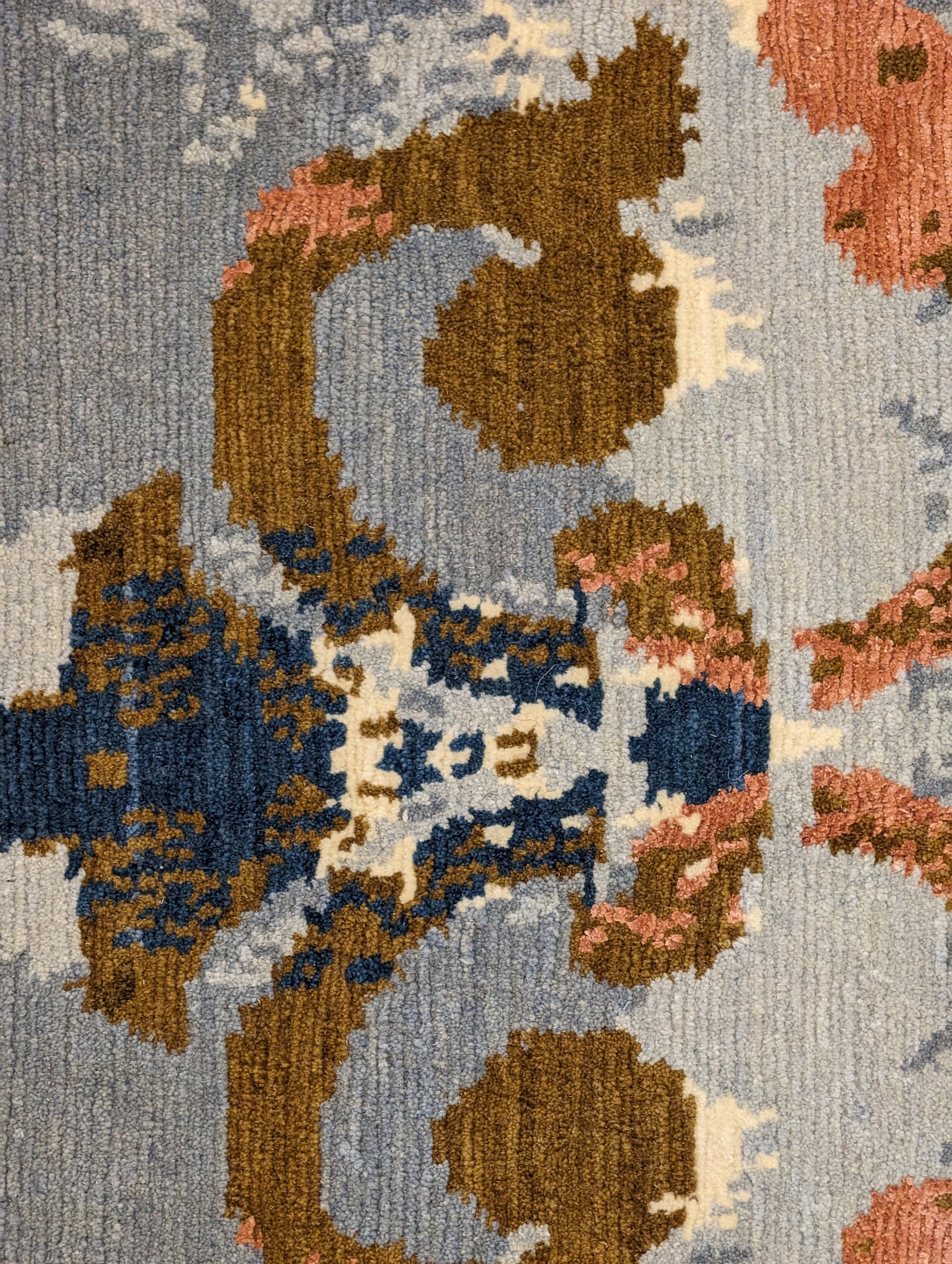 A hand-knotted rug with a luxurious blend of knots, featuring a palette of blues, salmon, ivory, brown, and gold. Wool and silk. 