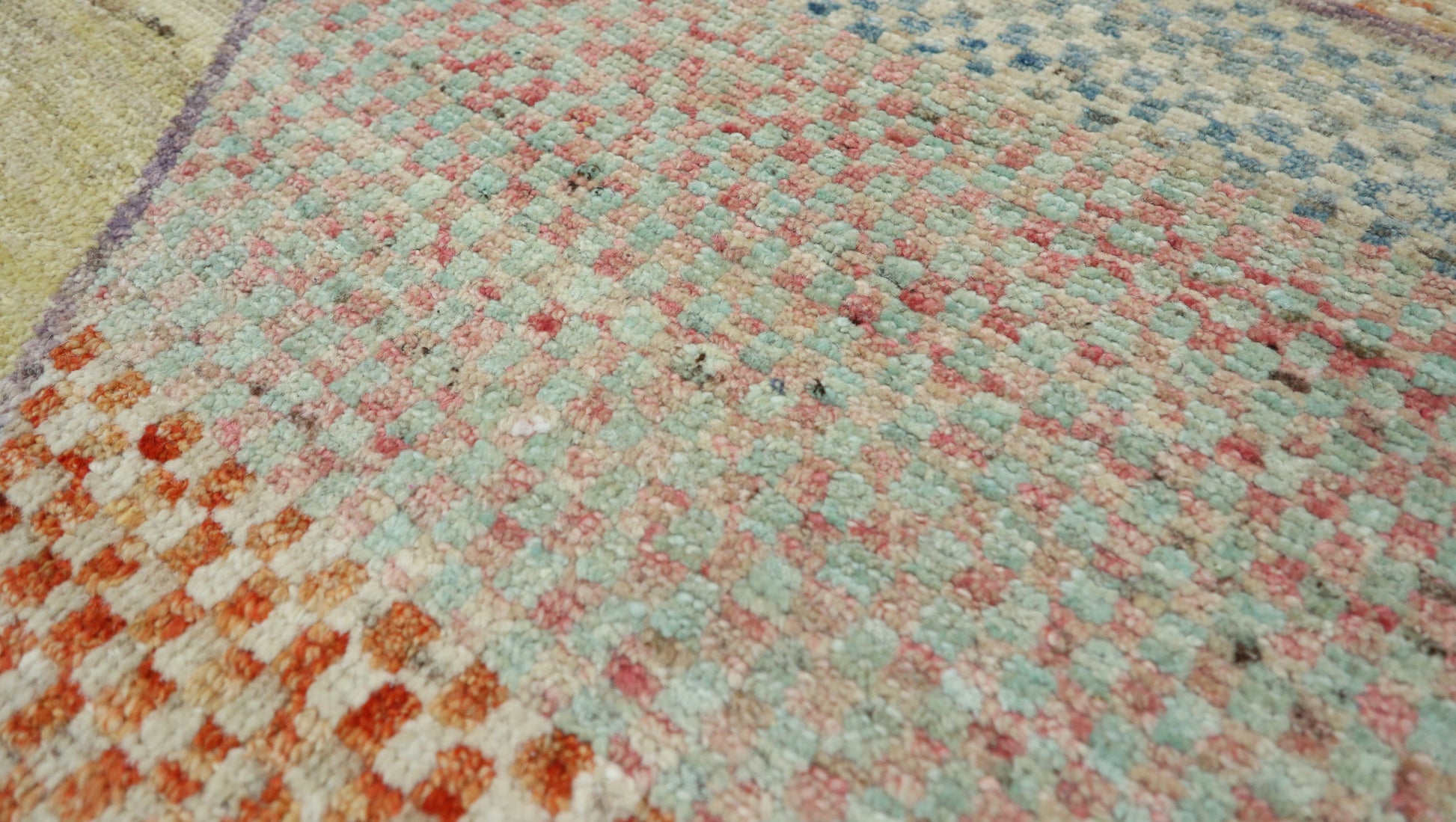 Hand-knotted geometric wool rug in sun-warmed sand and driftwood beige with hazy blue, sage green, and sunset blush accents.