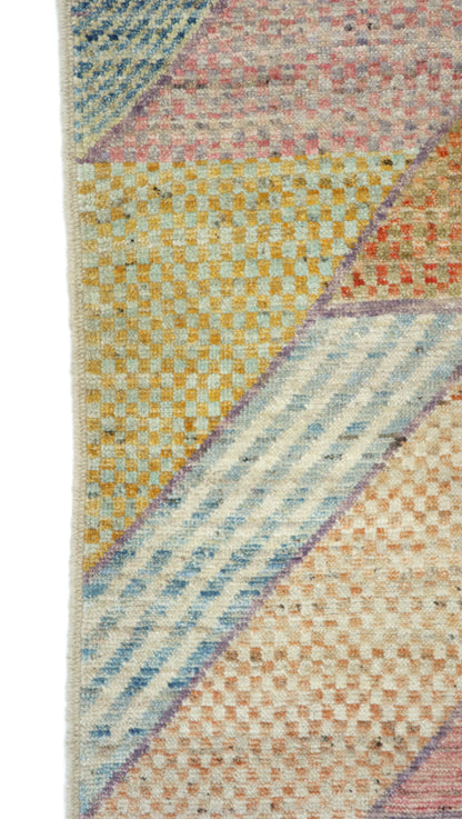 Hand-knotted geometric wool rug in sun-warmed sand and driftwood beige with hazy blue, sage green, and sunset blush accents.
