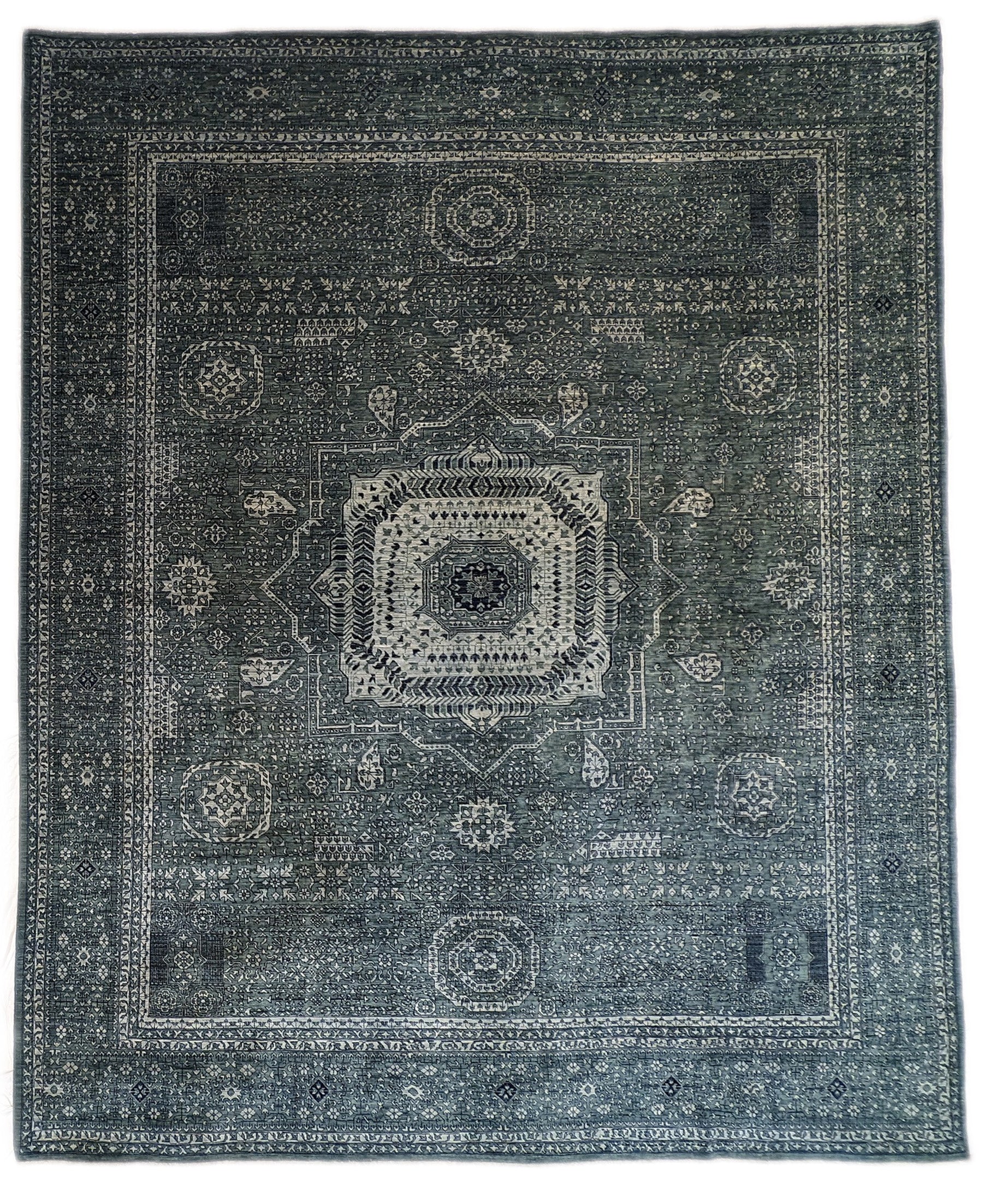 A hand-knotted wool rug with a geometric pattern in smokey green, deep navy, and crisp ivory colors.