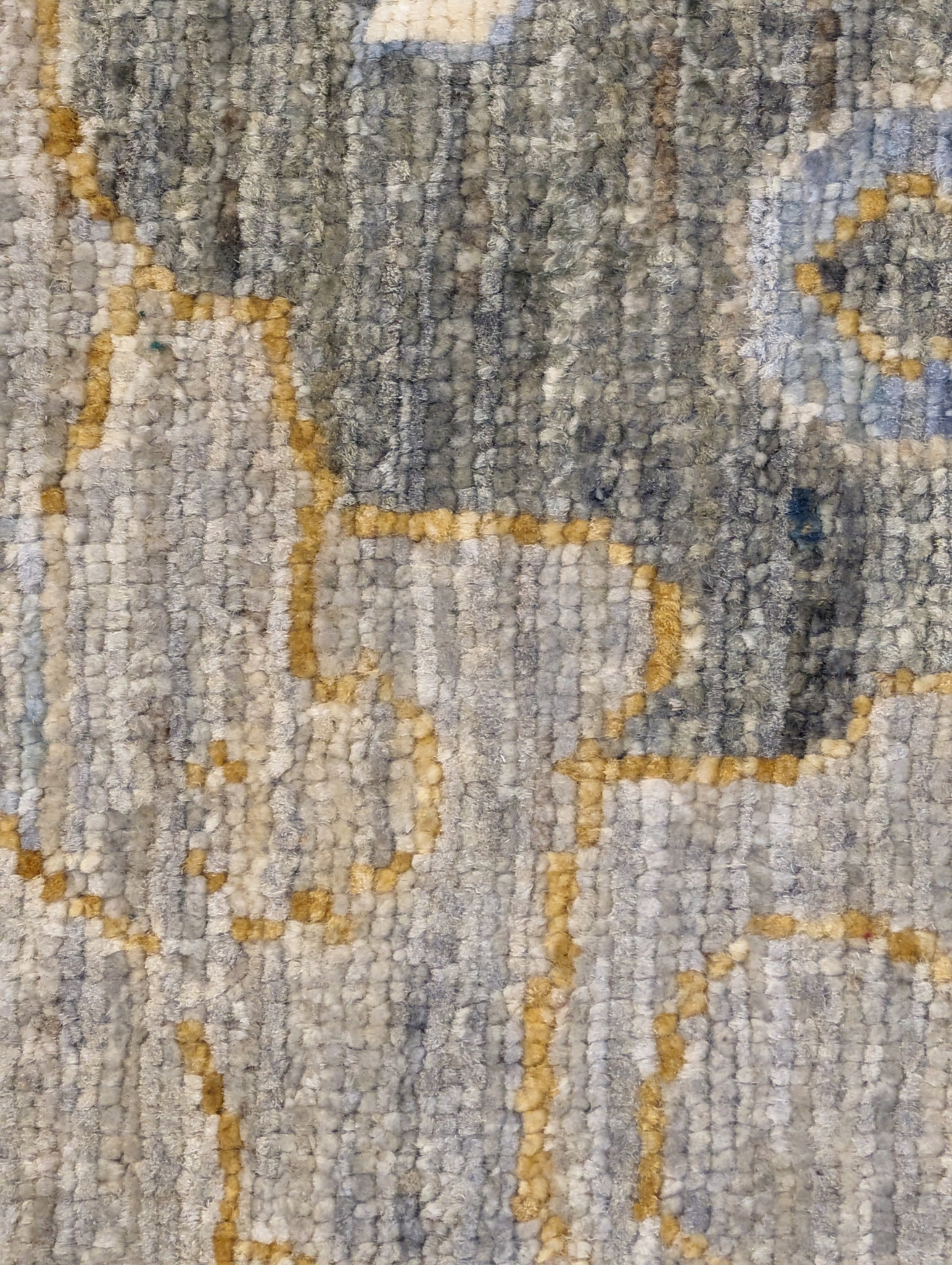 A hand-knotted wool rug with a coastal design in shades of beige, blue, brown, gold, ivory, navy, and sandy grey.