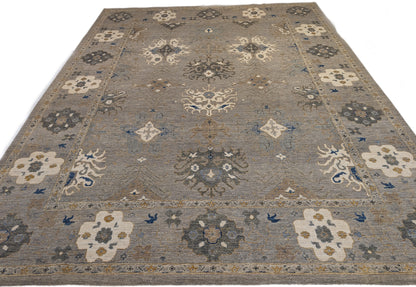 A hand-knotted wool rug with a coastal design in shades of beige, blue, brown, gold, ivory, navy, and sandy grey.