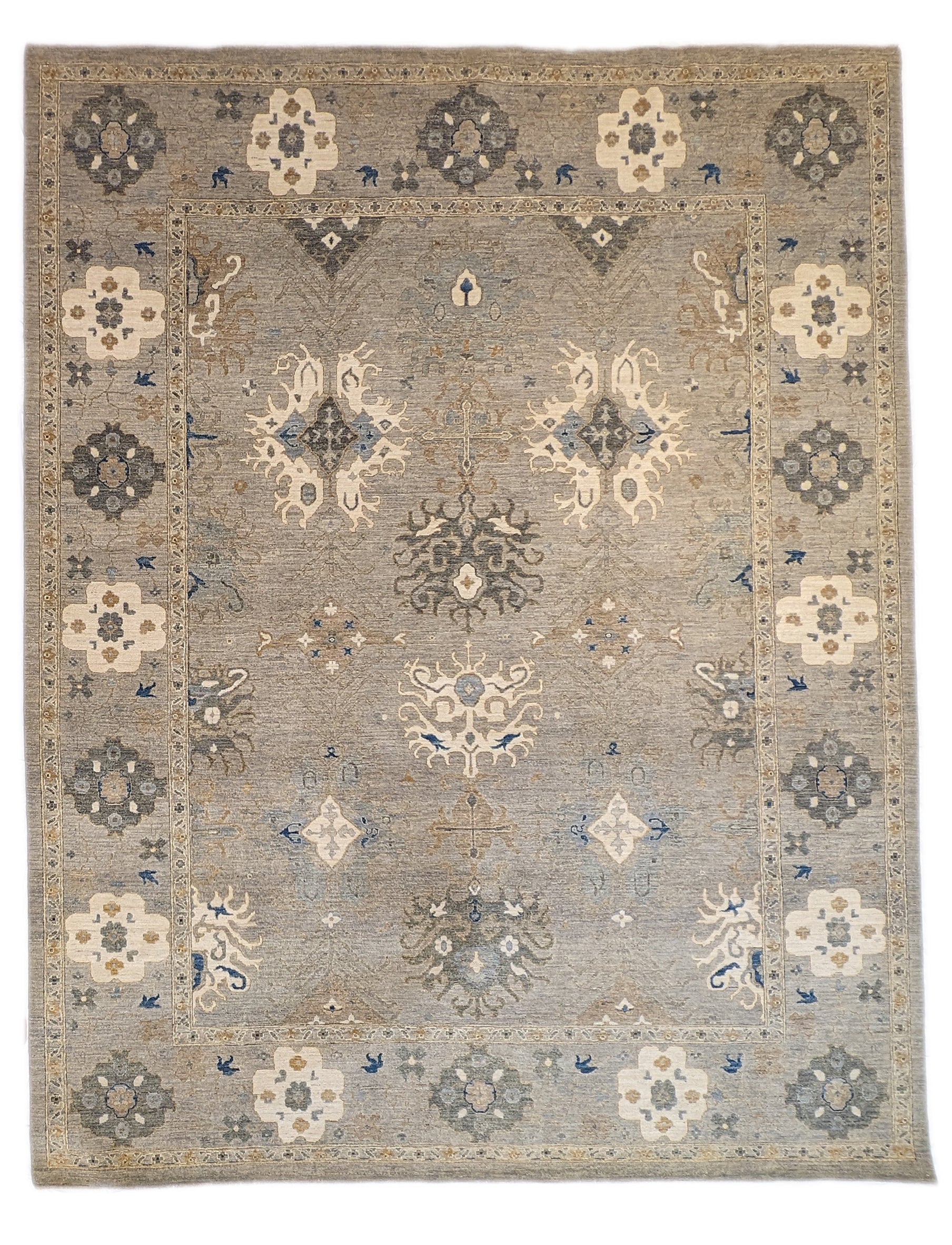 A hand-knotted wool rug with a coastal design in shades of beige, blue, brown, gold, ivory, navy, and sandy grey.
