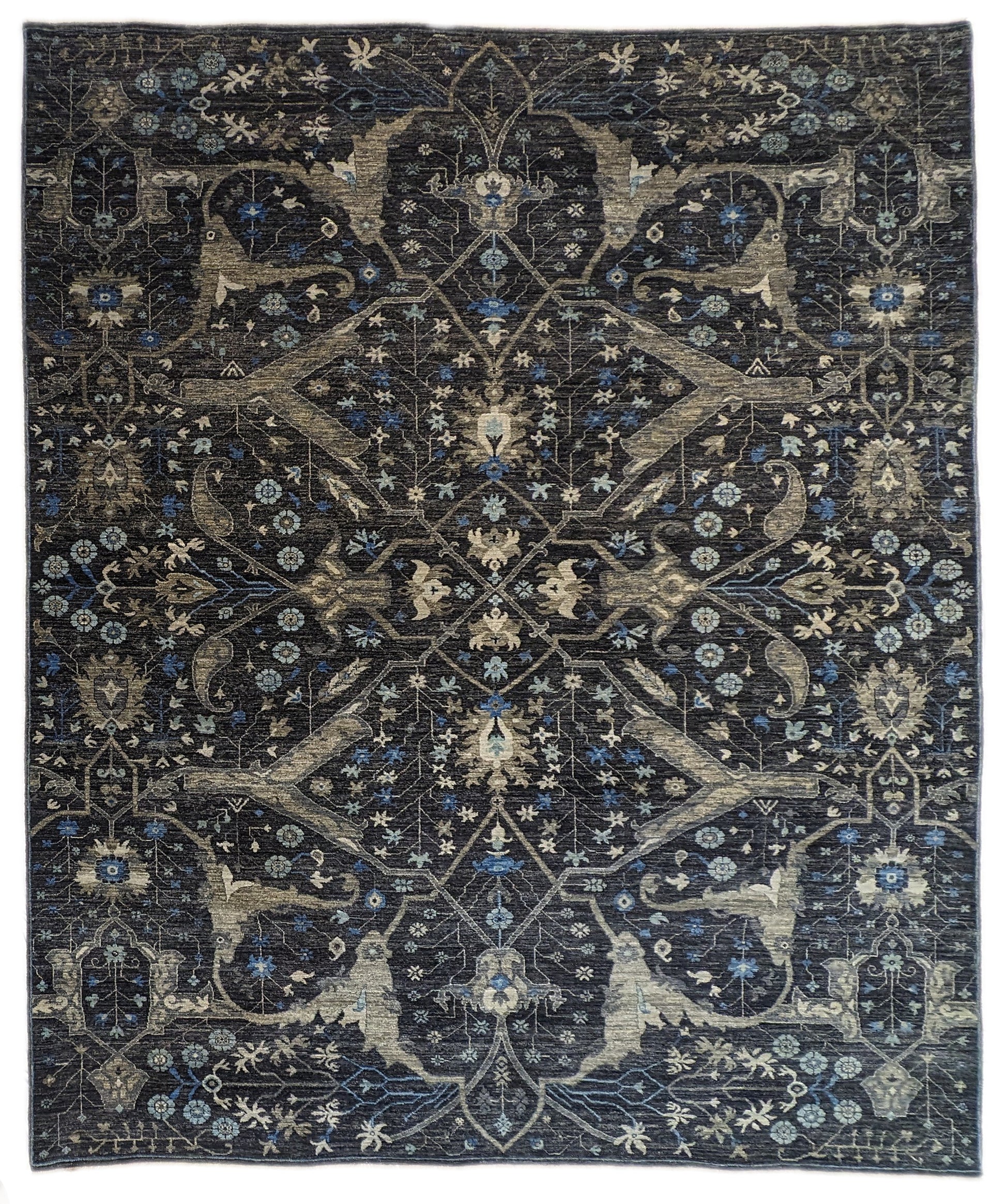 A hand-knotted wool rug with a complex pattern featuring coastal hues of navy, grey, blue, and ivory, and traditional motifs.
