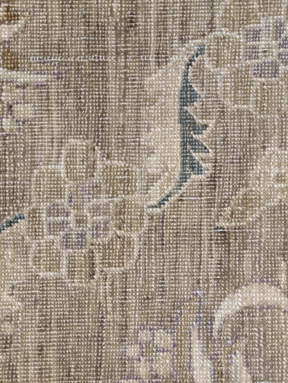 A hand-knotted wool rug with a traditional and coastal design in beige, brown, green, and other colors.