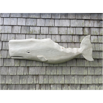 Wooden whale sculpture on a shingled wall